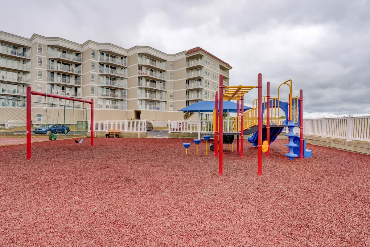 This exterior shot showcases the on-site playground, with swings and various play structures in front of the building facade. Children are visible at play, capturing the energy and joy of family gatherings and outdoor fun.